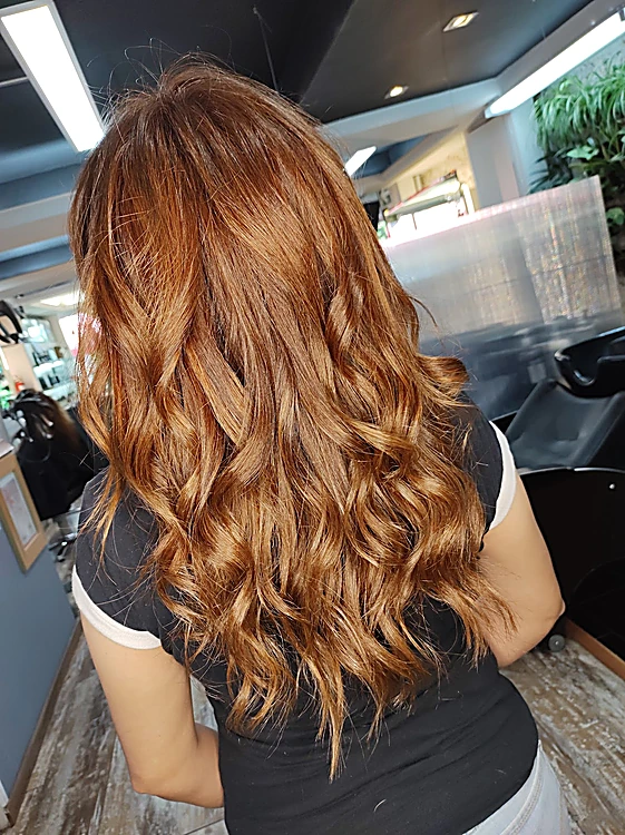 Cabello cobrizo largo en ondas, de espaldas dentro del salón